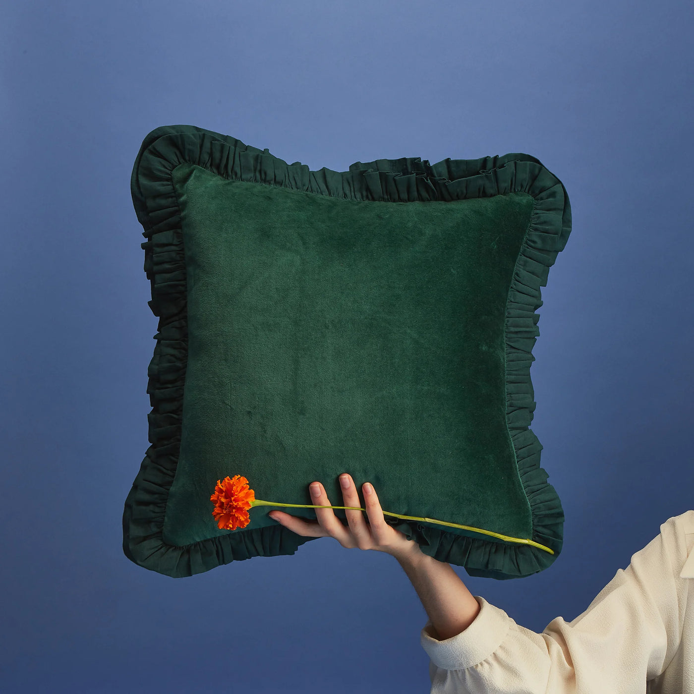 Maison Splendid green frill cushion being held by a hand with flower