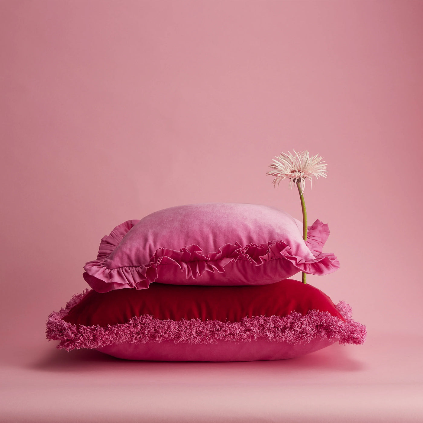 Maison Splendid pink velvet frill cushion on top of oblong velvet red cushion
